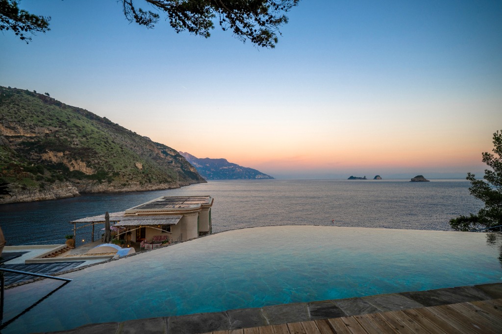 Intimate private island infinity pool overlooking the ocean at sunset for a romantic honeymoon escape