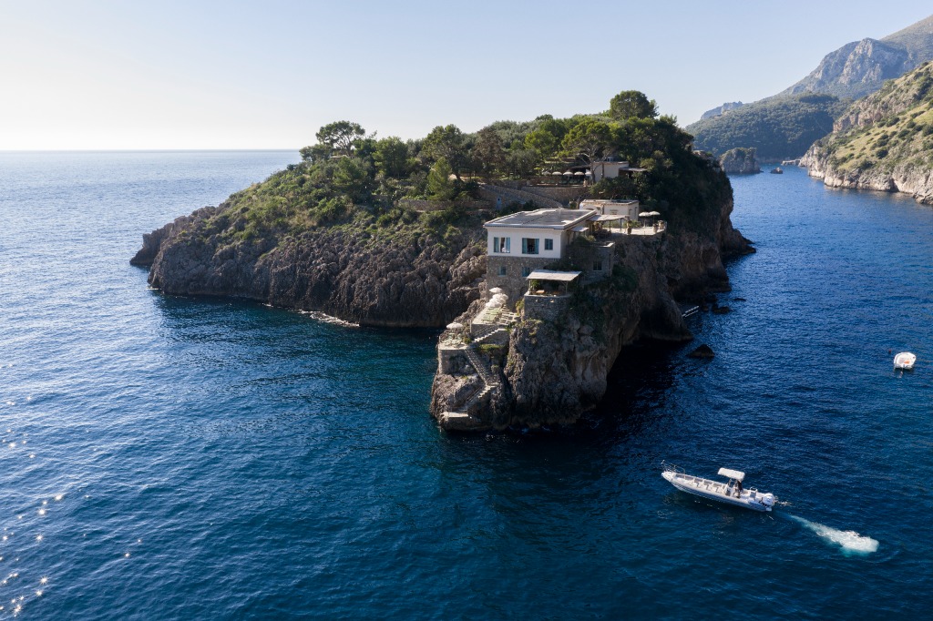 Exclusive private island villa compound with an approaching motor yacht